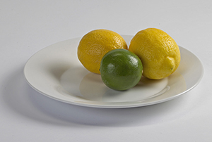 Two lemons and a lime on plate.