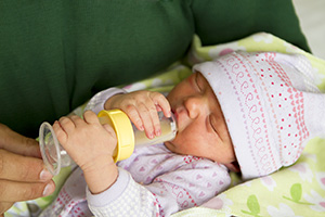 Newborn baby being bottle fed.