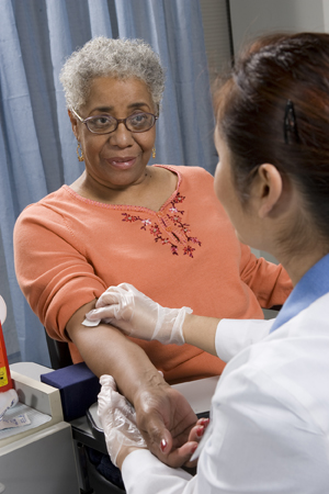 Proveedora de atención médica extrayendo una muestra de sangre del brazo de una mujer.