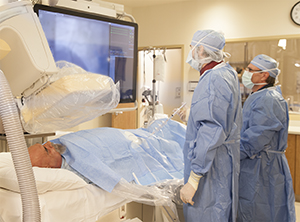 Dos técnicos realizan una angiografía en un paciente.