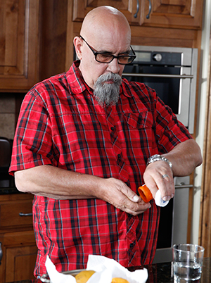 Un hombre toma pastillas en la cocina.