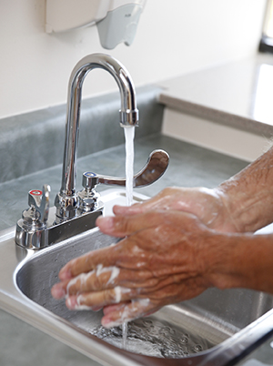 Primer plano de lavado de manos con agua y jabón en un lavabo.