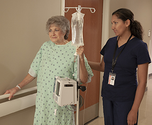 Mujer que camina en el hospital con un proveedor de atención médica.