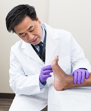 Health care provider examining the bottom of a foot.