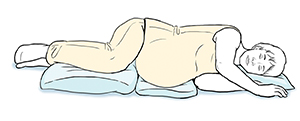 Embarazada acostada de lado con almohadas que le sostienen las rodillas, el abdomen y la cabeza.