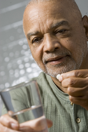 Hombre que sostiene un vaso de agua, preparándose para tomar una píldora.
