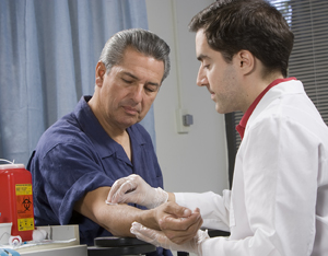 Un proveedor de atención médica toma una muestra de sangre del brazo de un hombre.