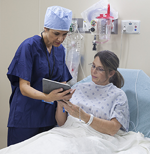 Un proveedor de atención médica habla con una mujer en la sala de preparación preoperatoria del hospital.