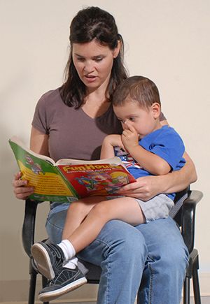 Mujer con un niño en el regazo, le está leyendo un cuento.