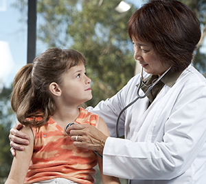Proveedor de atención médica escuchando los sonidos del pecho de una niña con un estetoscopio.