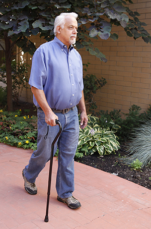 Hombre caminando al aire libre con un bastón.